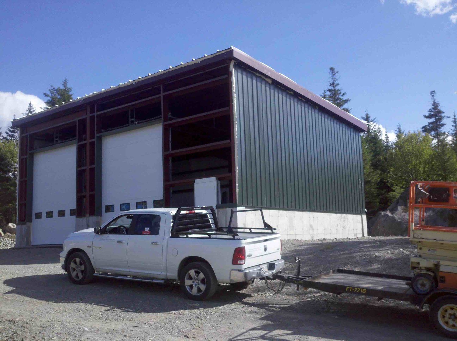 A white truck is parked in front of a building with a trailer attached to it.