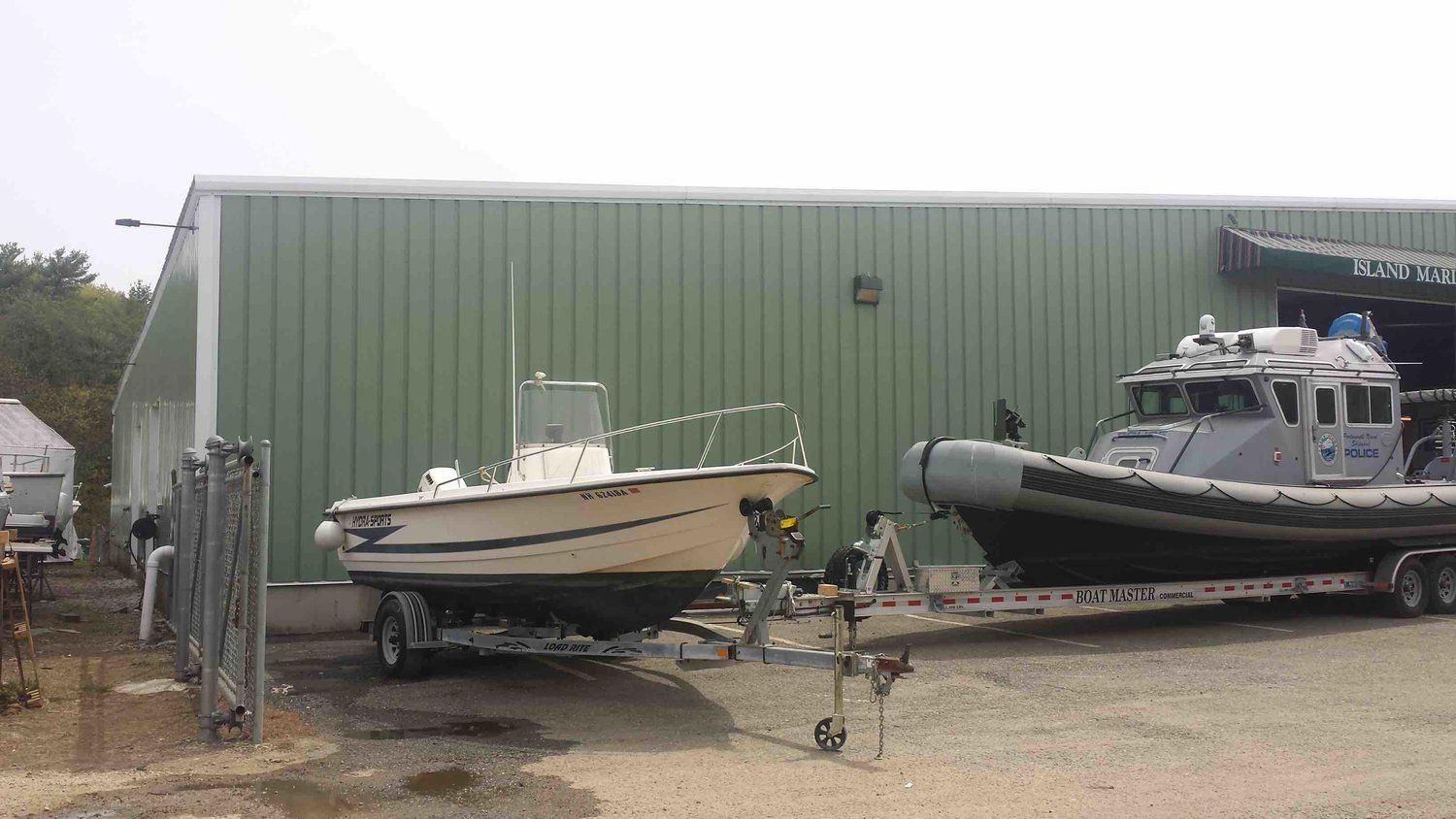Two boats are parked in front of a green building.