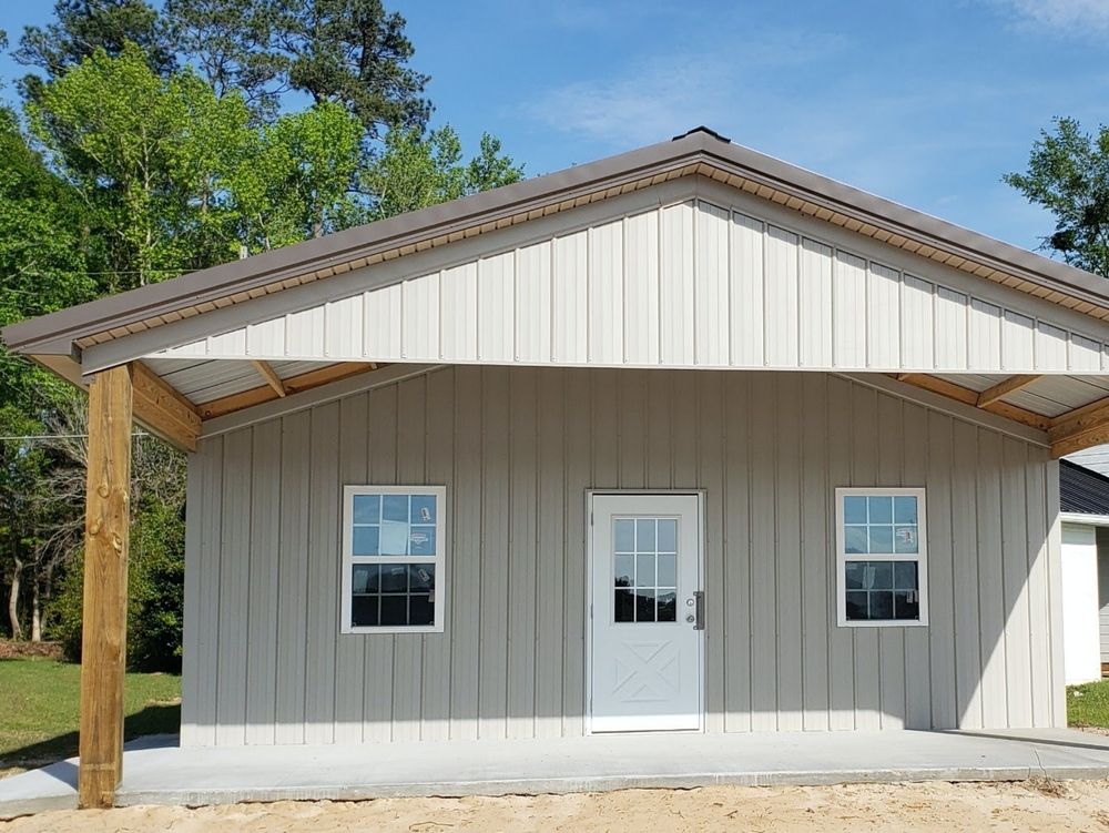 A gray and white metal building with a porch and windows.