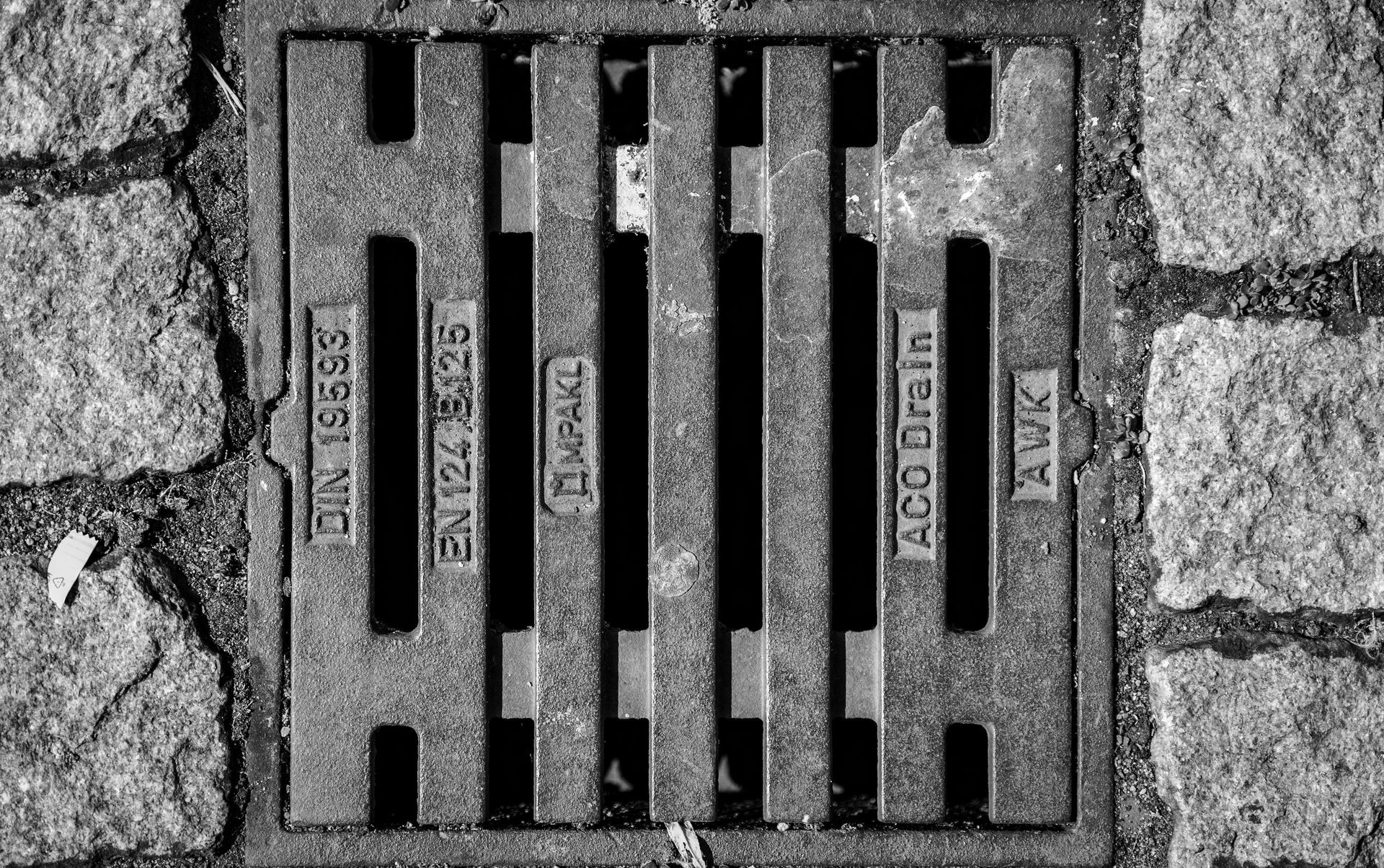 Blue-gloved hand lowers a green hose into a round underground tank or well.