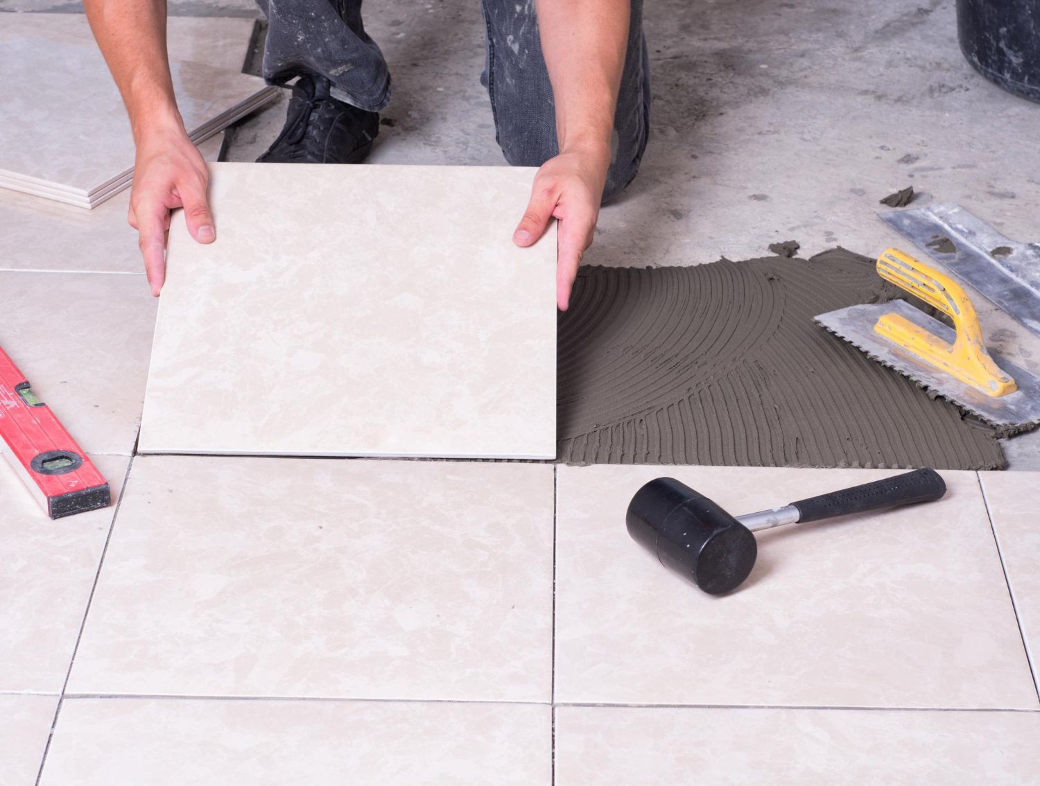 A person is laying a tile on the floor.