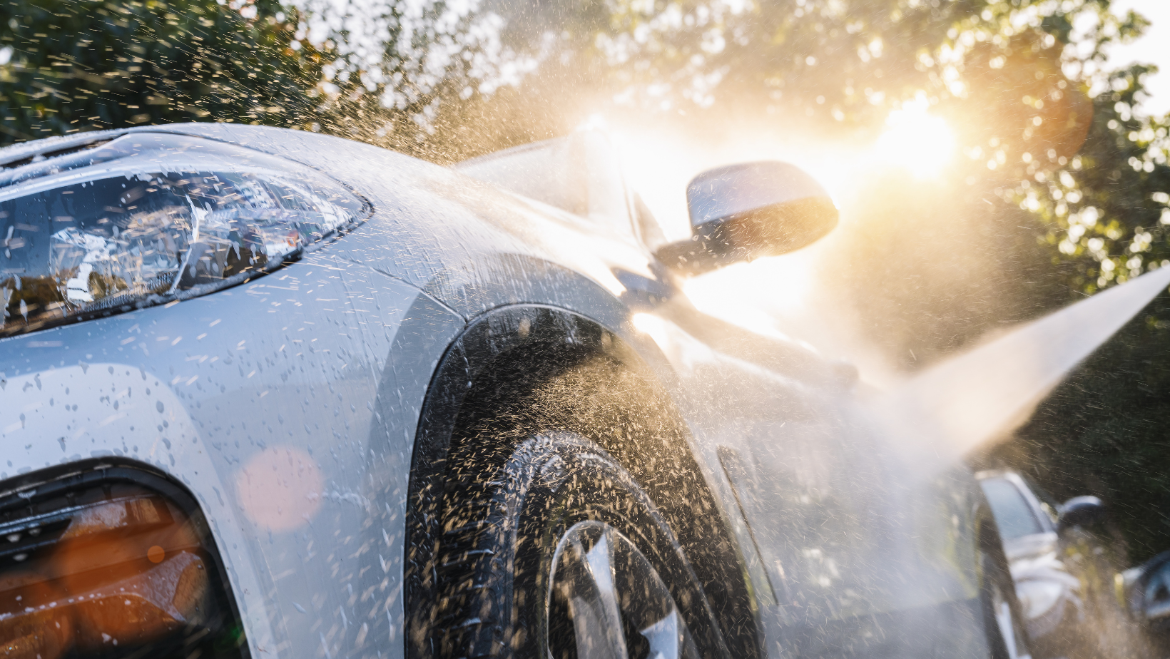 A car is being washed with a high pressure washer.