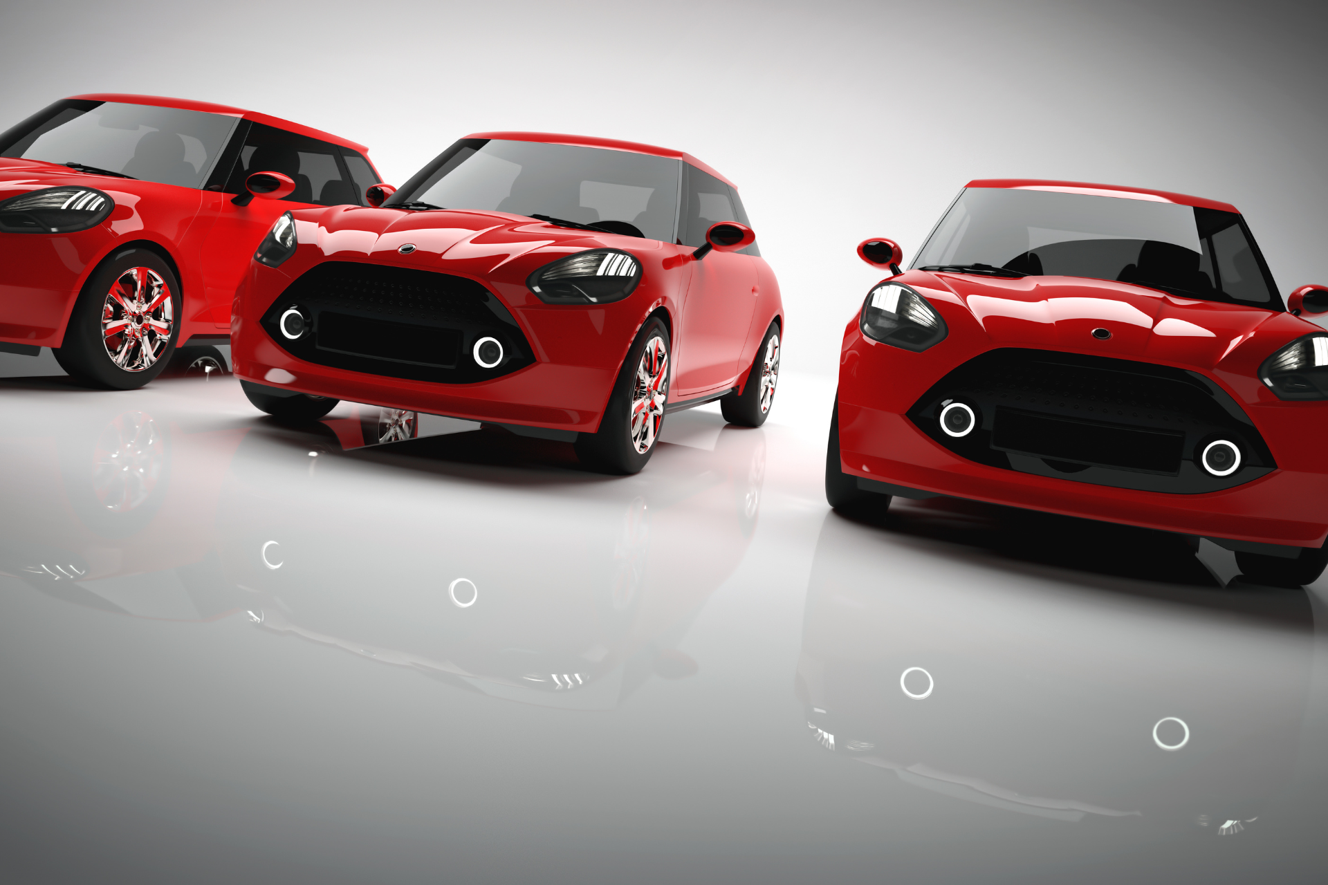 Three red cars are parked next to each other on a white surface.