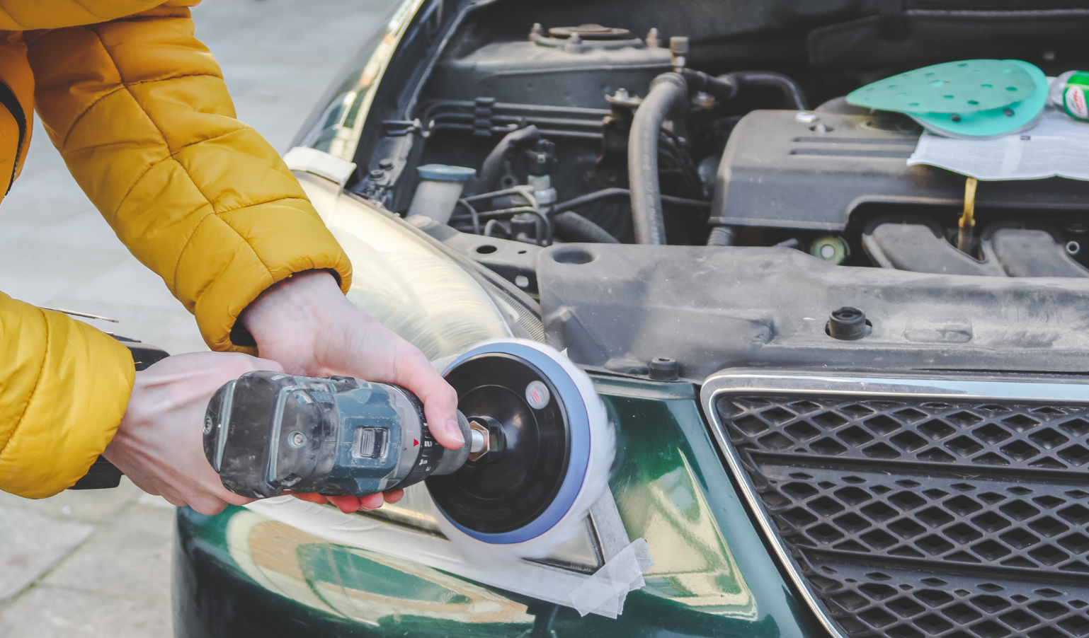 A man is polishing a car with a polisher.