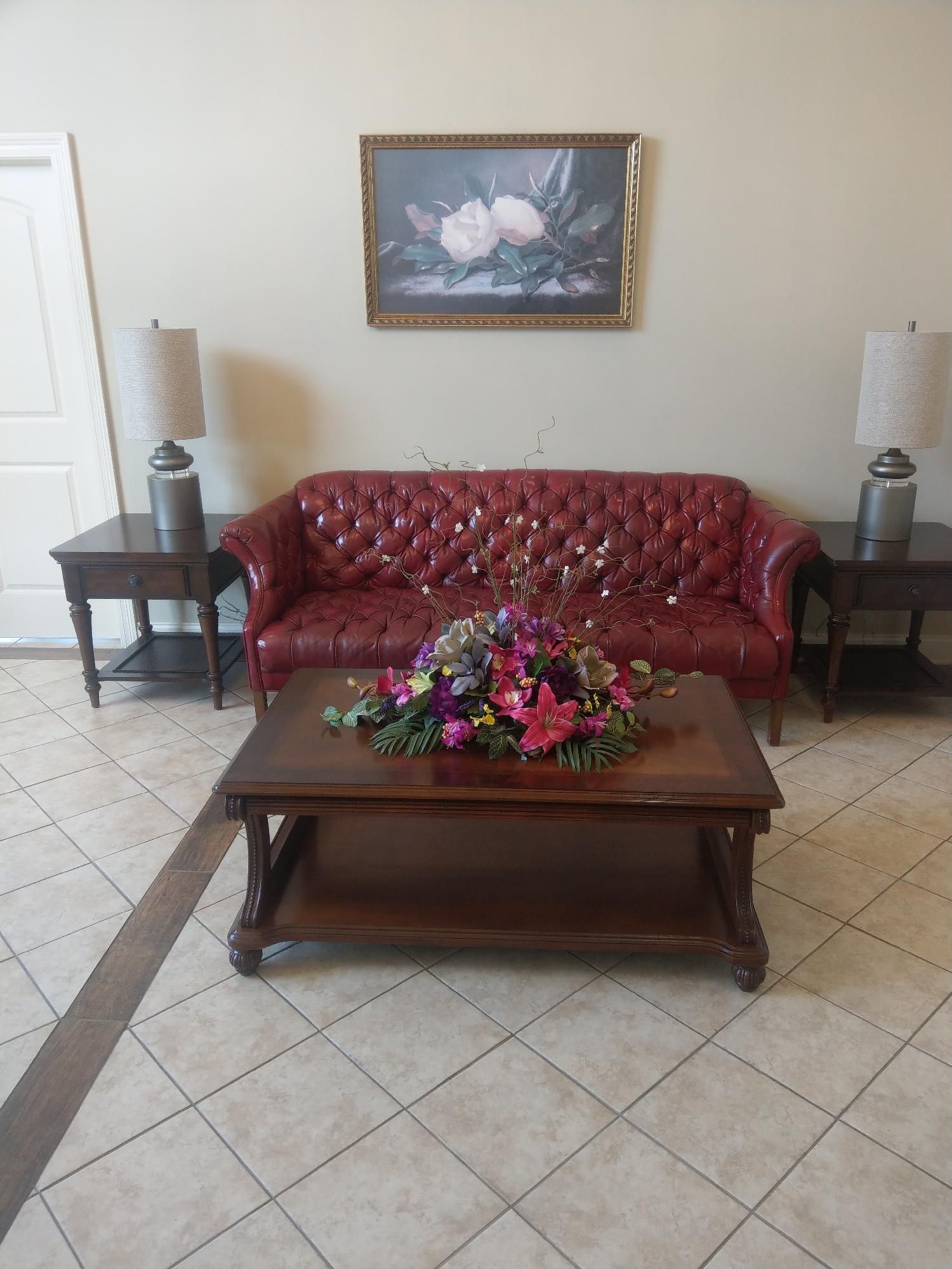 Living room with red sofa, coffee table with flowers, and matching side tables with lamps.