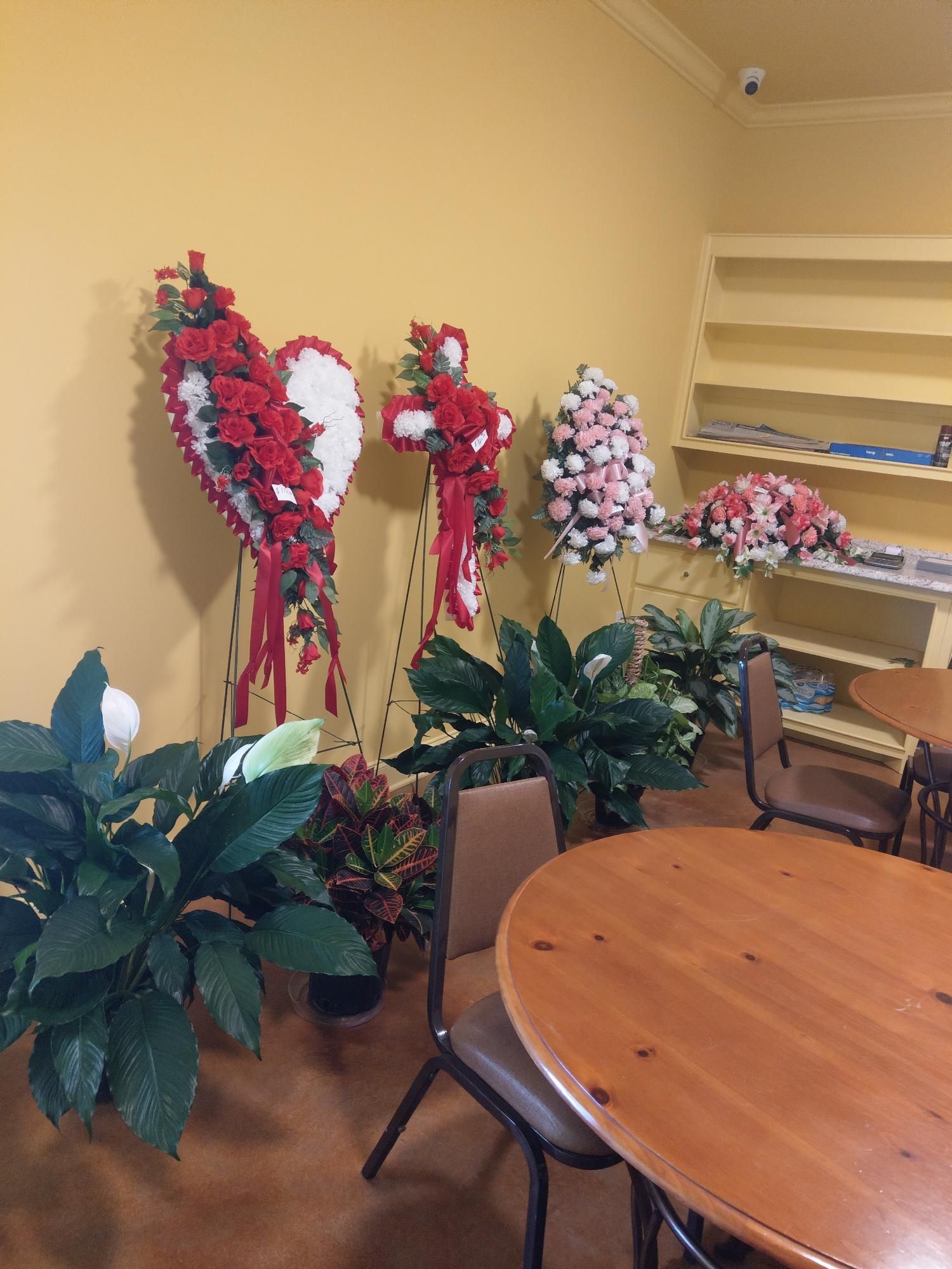 Dining room with round table, chairs, and large floral arrangements against a yellow wall.