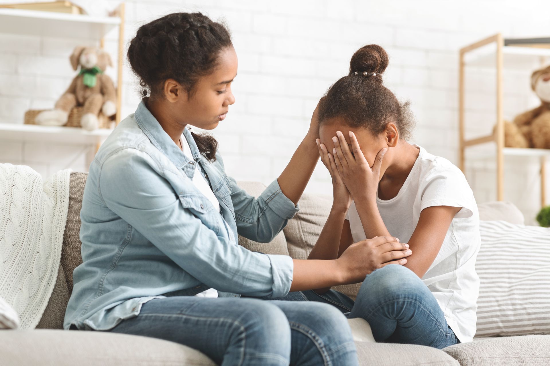 Person comforting a child on a couch in a bright living room
