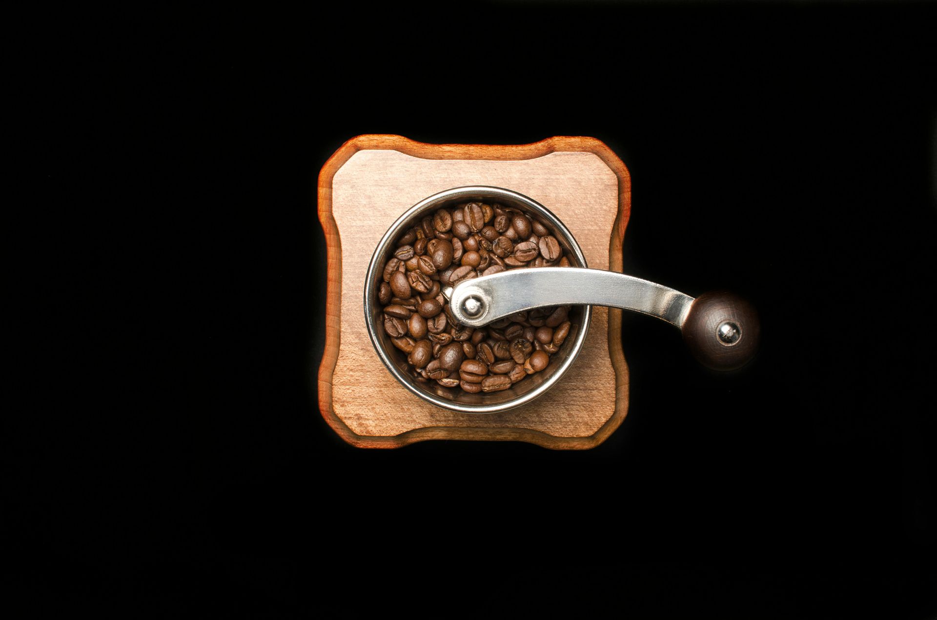 Top-down view of a manual coffee grinder filled with coffee beans, symbolizing slow living and mindful ritual.