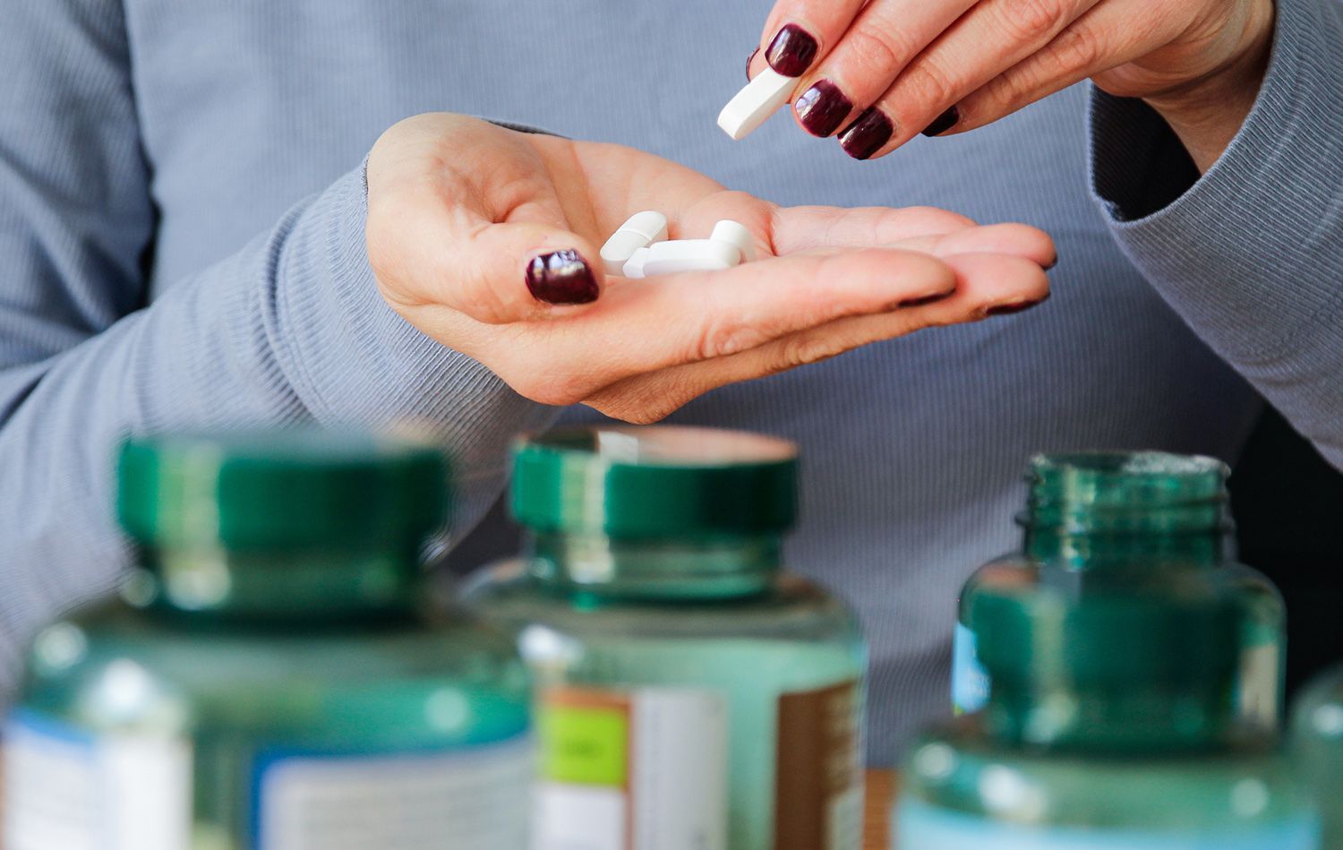 Woman holding white pills in her hand, taking medication from a bottle. Woman holding white pills in her hand, taking medication from a bottle.