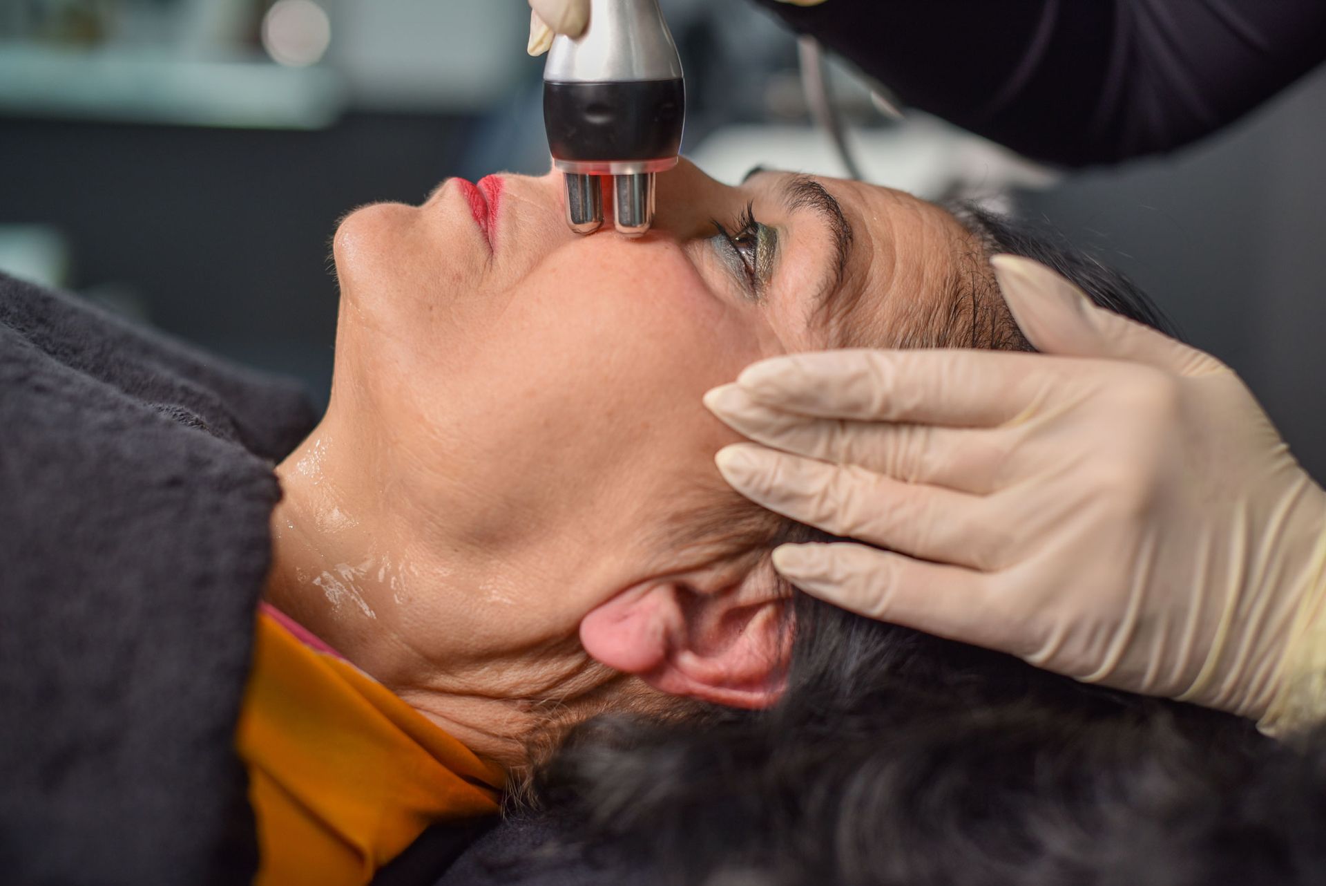 Woman receiving facial treatment with a handheld device, in a spa setting. Woman receiving facial treatment with a handheld device, in a spa setting.