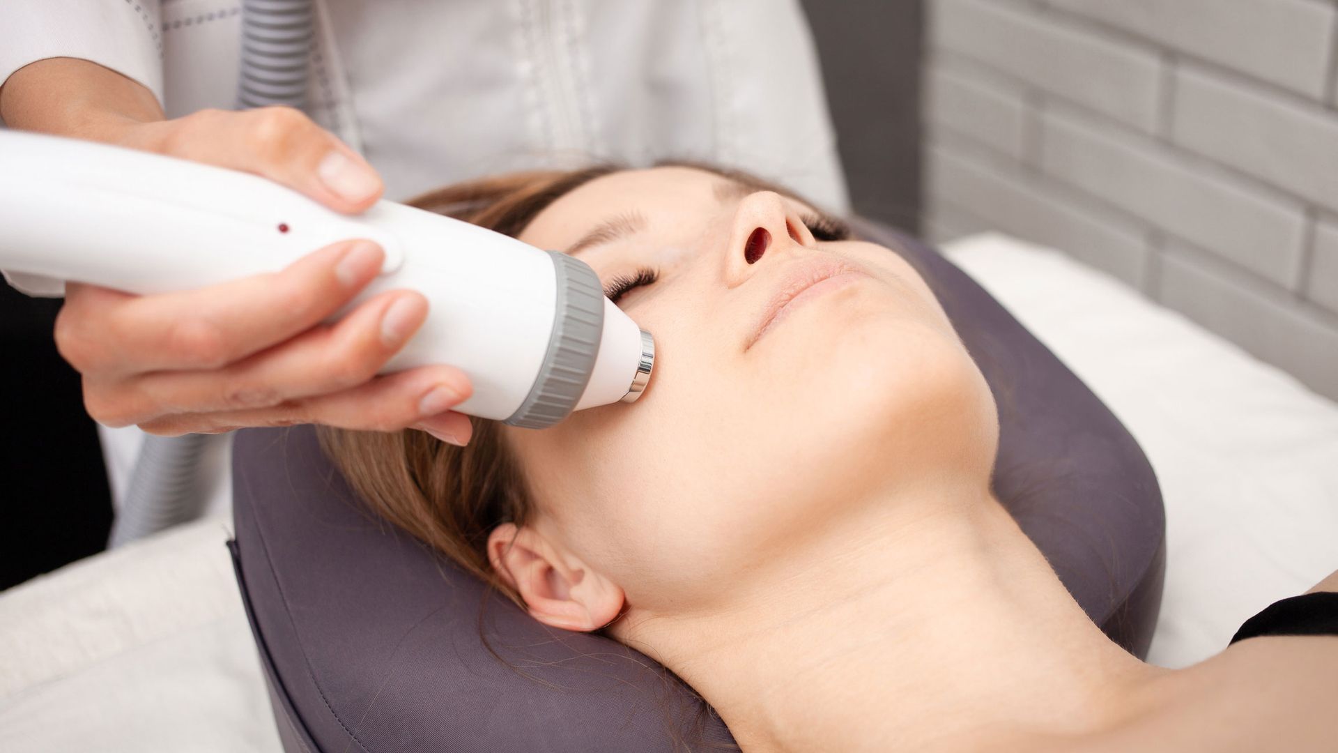 A person receiving facial skin treatment with a handheld device, indoors. A person receiving facial skin treatment with a handheld device, indoors.