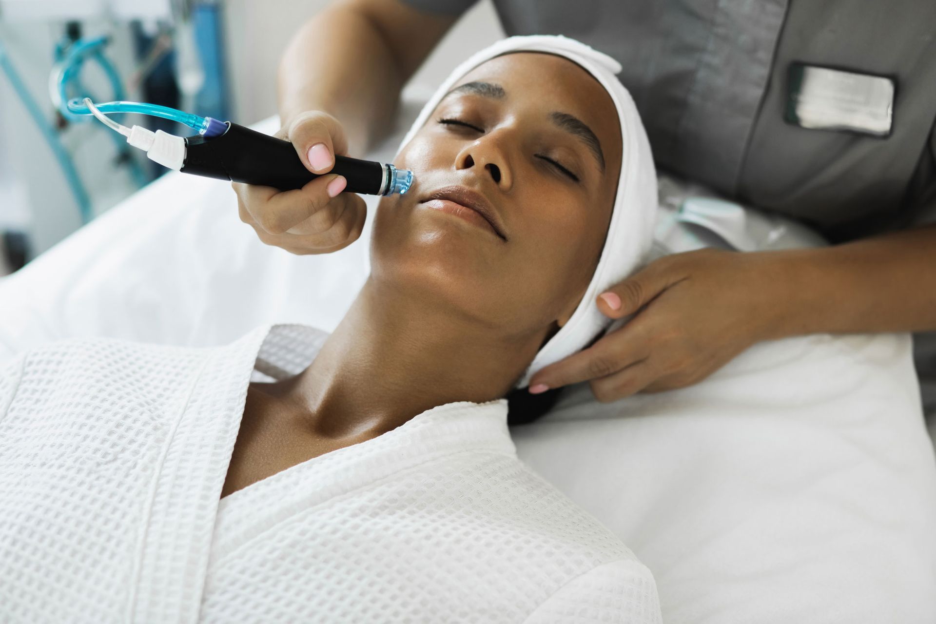 Woman receiving facial treatment in a spa, device applied to her face. Woman receiving facial treatment in a spa, device applied to her face.