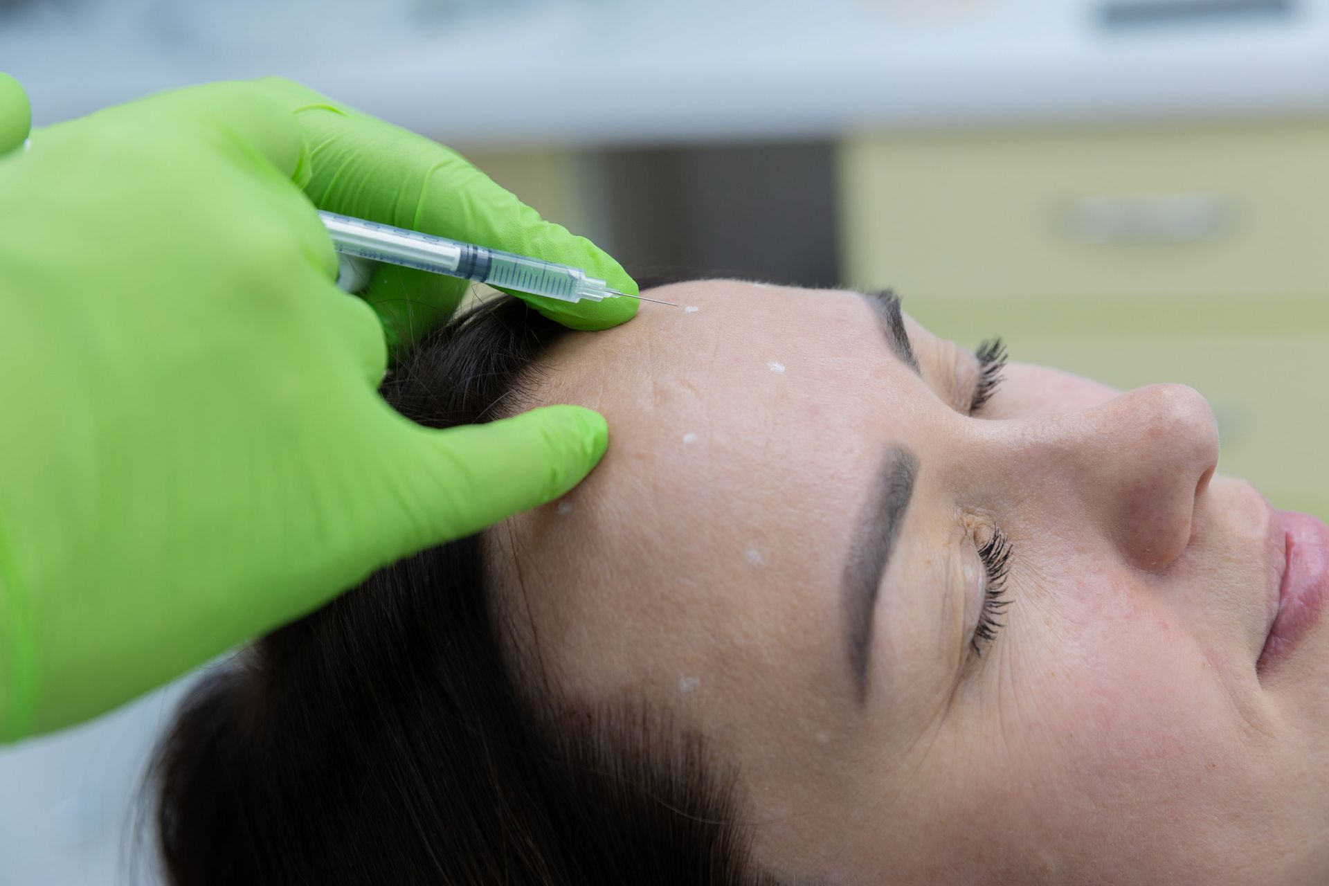 Person receiving a facial injection in a medical setting. Person receiving a facial injection in a medical setting.