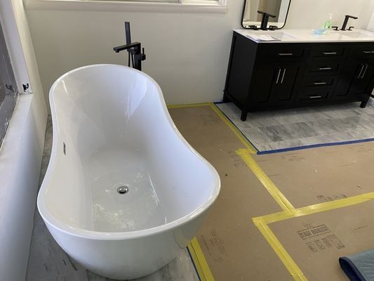 New soaking tub set in place with floor protection during a residential fire rebuild