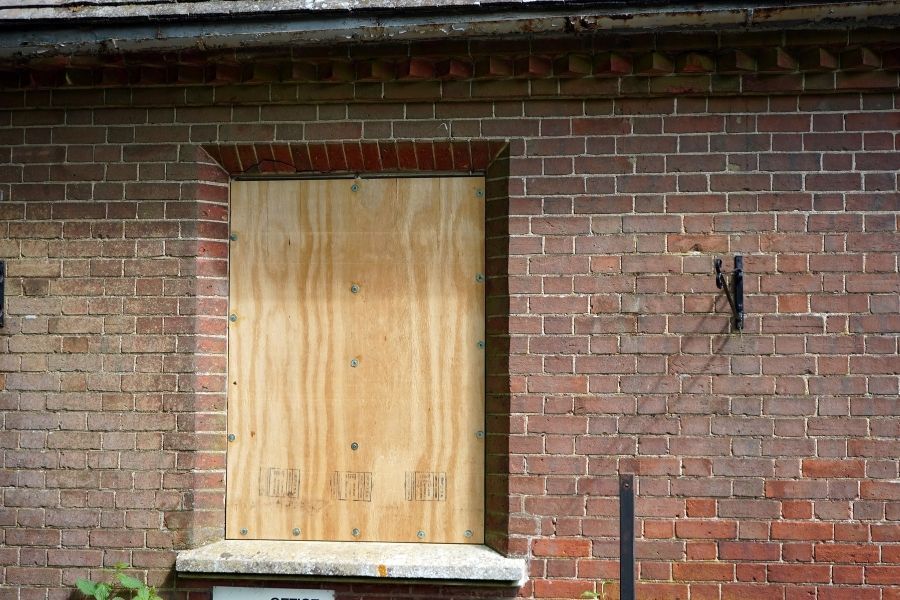 Plywood boards covering the windows and front door of a fire-damaged single-story home in Lake County, Florida