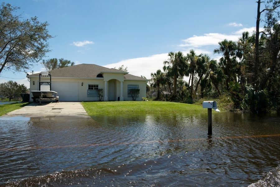 Floodwater covering the street and front yard of a single story Florida home after a hurricane