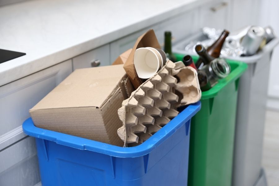 Kitchen recycling bins filled with cardboard and glass next to a counter as garbage disposal alternatives in The Villages FL