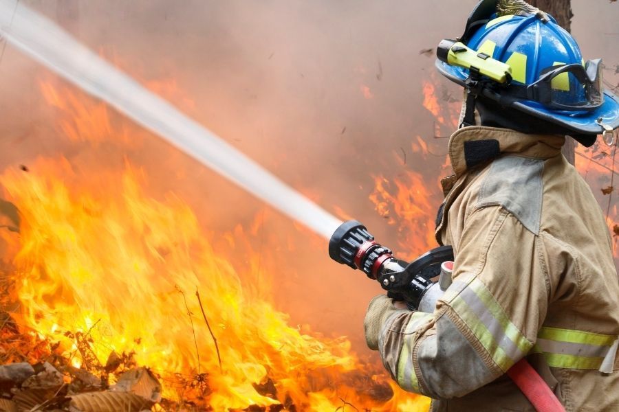 Firefighters directing high volume hose water into the front of a single story Central Florida home during a house fire