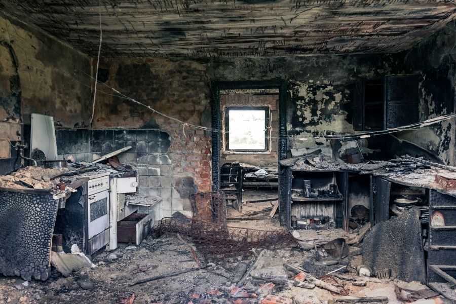 Severely fire damaged kitchen with charred ceiling, burned cabinets, and soot covered walls in a Central Florida home