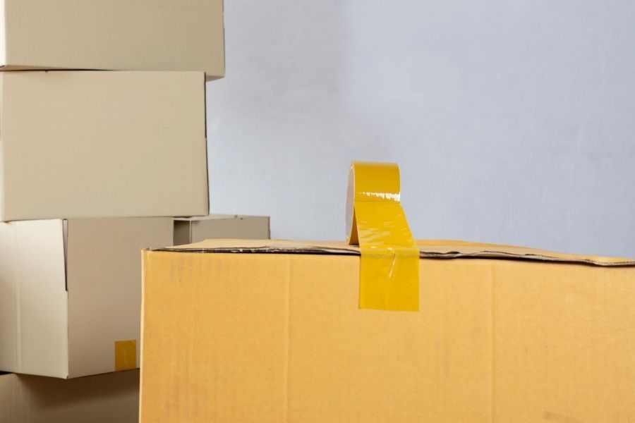 Stacked cardboard moving boxes with a roll of packing tape ready for a contents pack-out