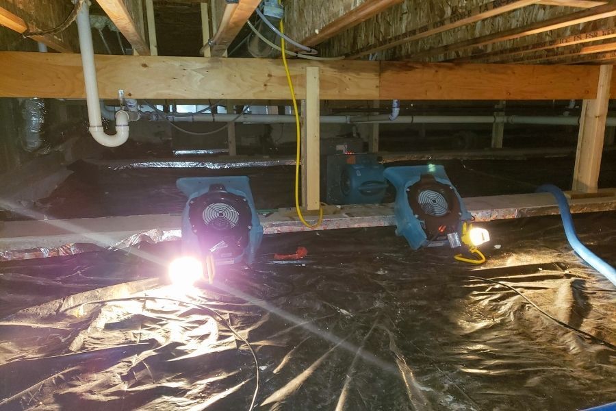 Two air movers and a work light running in a residential crawl space during a moisture remediation job in Tavares FL