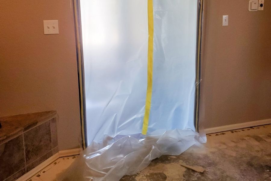 Plastic sheeting and HEPA air scrubbers set up around a contained mold remediation work zone in a home