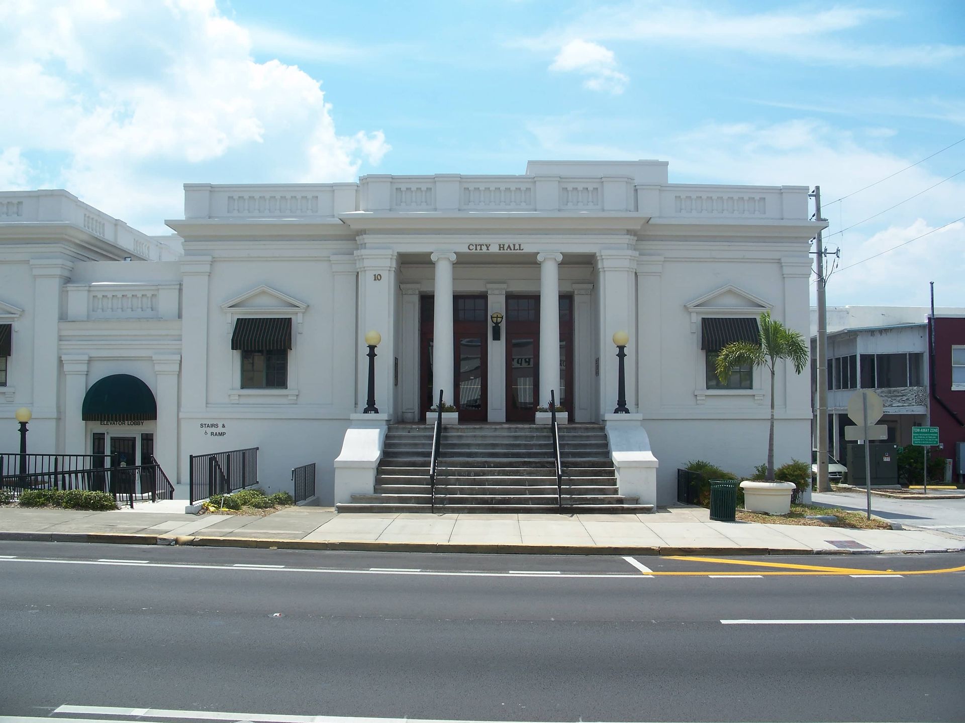 White building with two pillars and stairs under a bright blue sky in Eustis, FL.