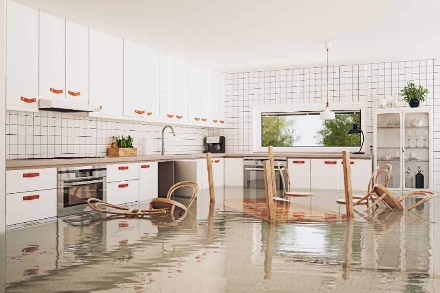 Flooded kitchen with overturned chairs after water line failure in Orange County