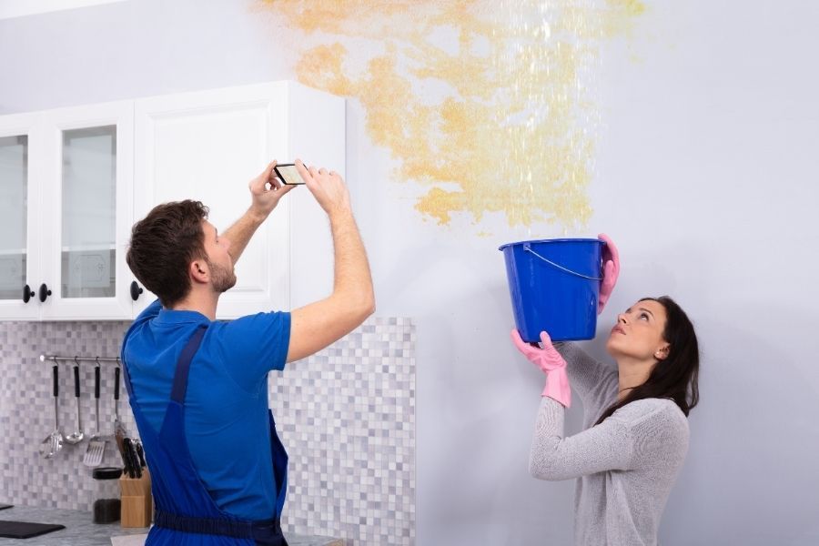 Homeowner documenting water damage with a phone camera before starting DIY cleanup