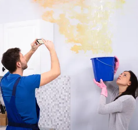 An expert from FFF's Team inspects water damage while a colleague holds a bucket in St. Petersburg, FL