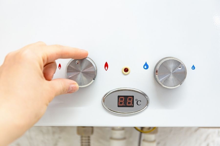 Hand adjusting water heater temperature control panel