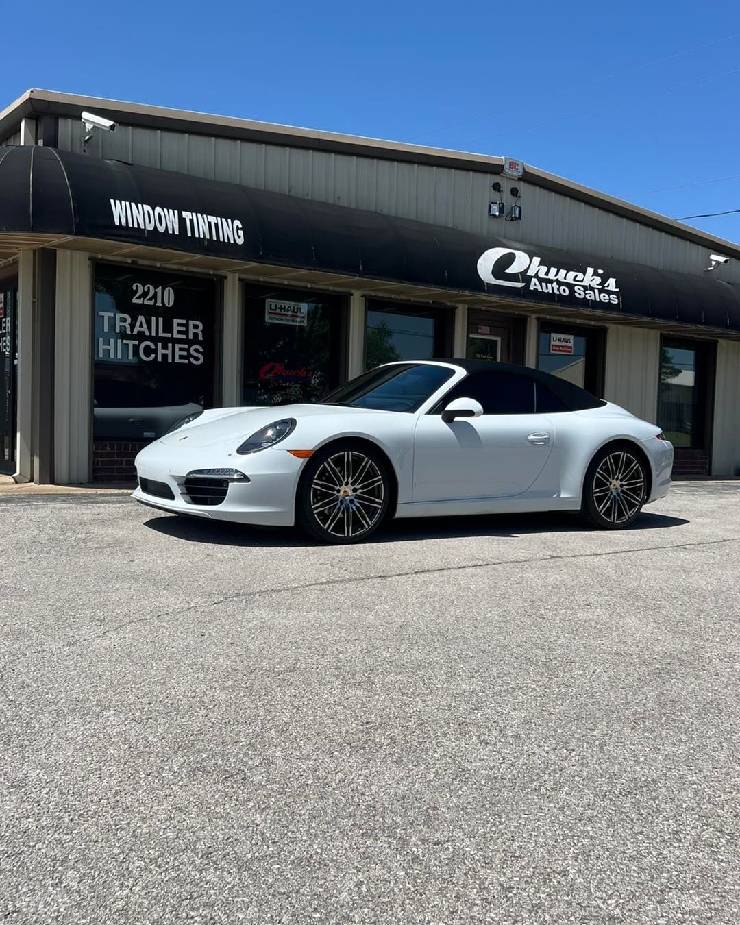 White Porsche convertible parked in front of a business with