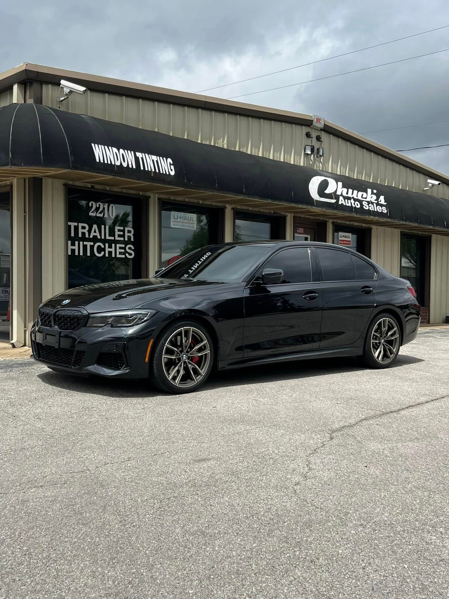 Black BMW sedan parked in front of a building with a black awning and