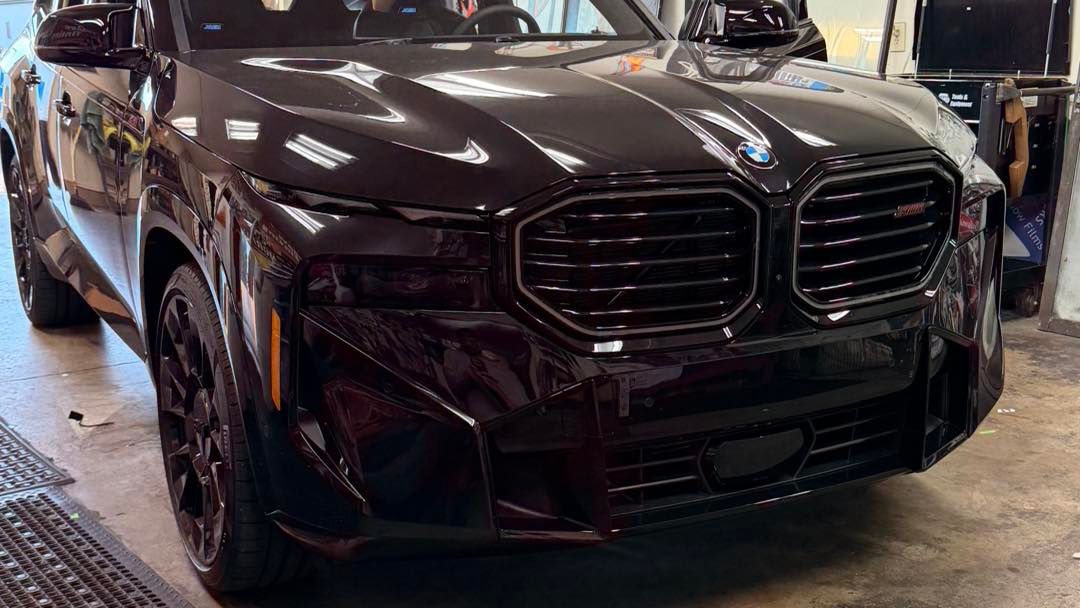Dark burgundy BMW XM SUV parked in a garage.