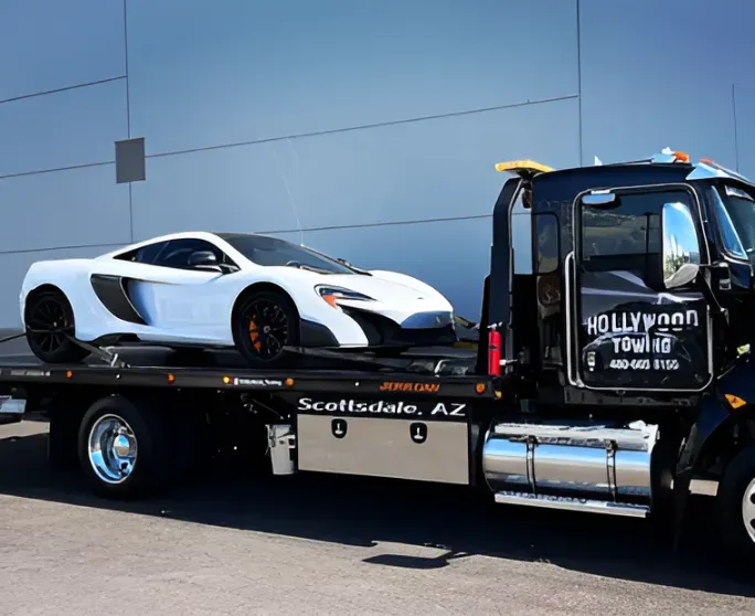 White sports car on a flatbed tow truck in Scottsdale, AZ, with Hollywood Tow branding