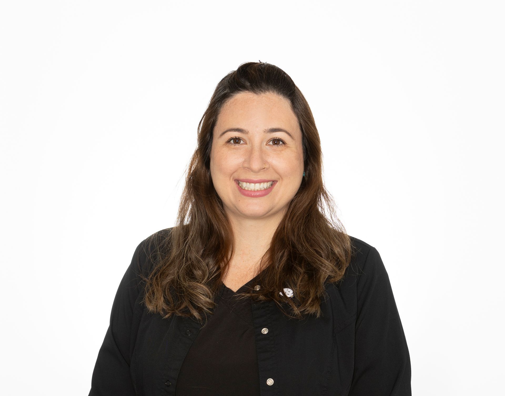 A woman in a black scrub top is smiling for the camera.