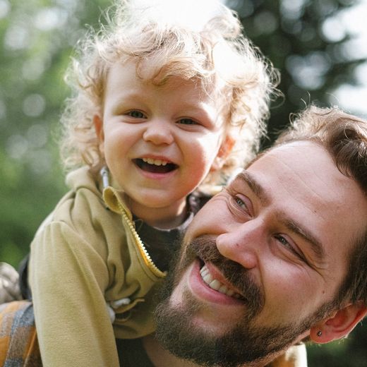 A man is carrying a little girl on his shoulders.