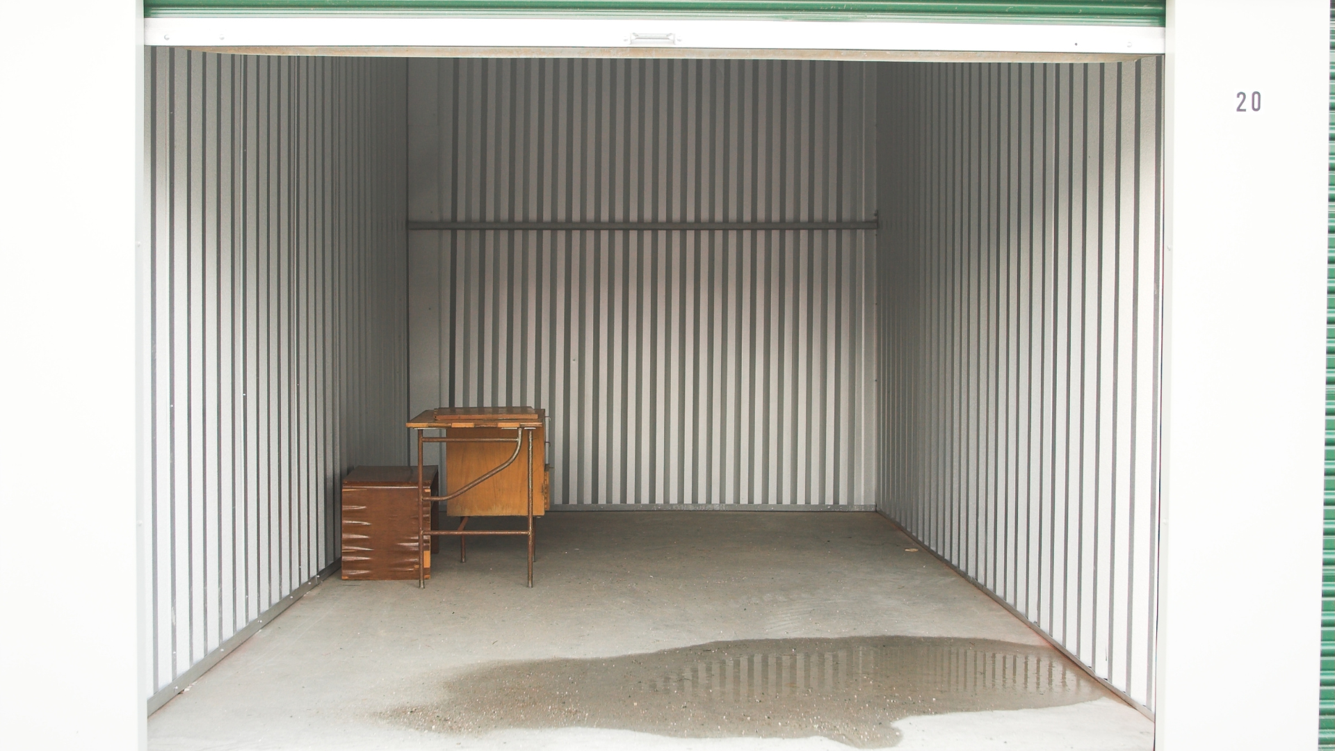 Interior of a storage unit facility with white doors lining a long hallway, lit by overhead lights.