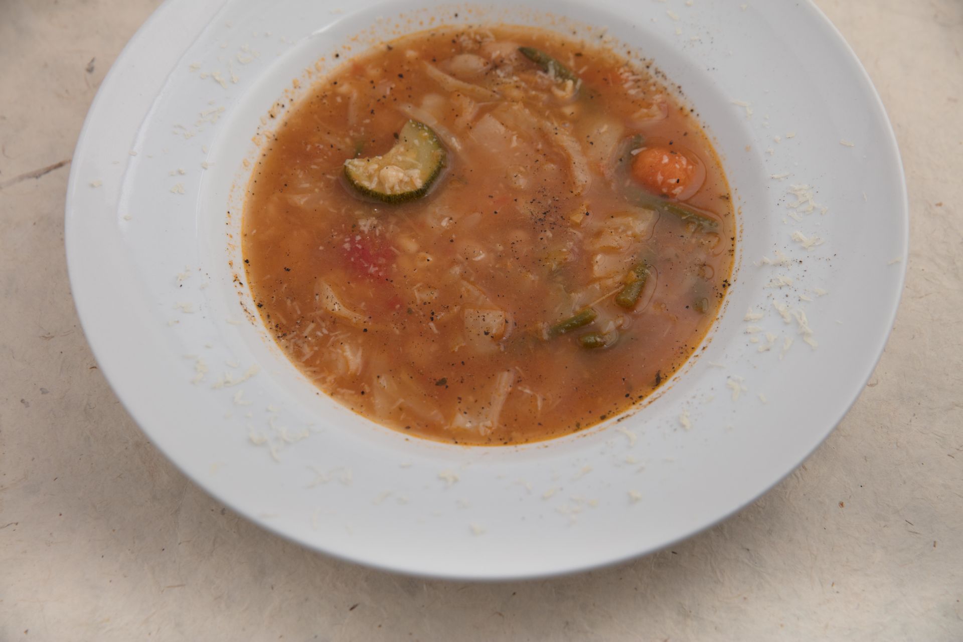 Ciotola di zuppa di verdure con zucchine, carote e fagioli bianchi.