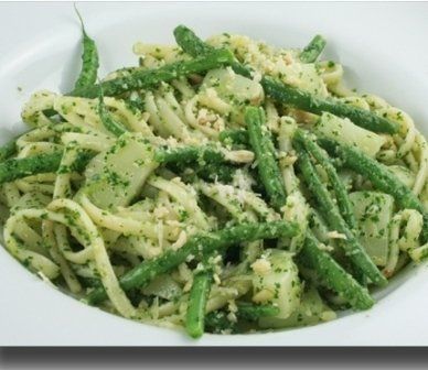 Piatto di pasta con fagiolini e pesto, in una ciotola bianca.