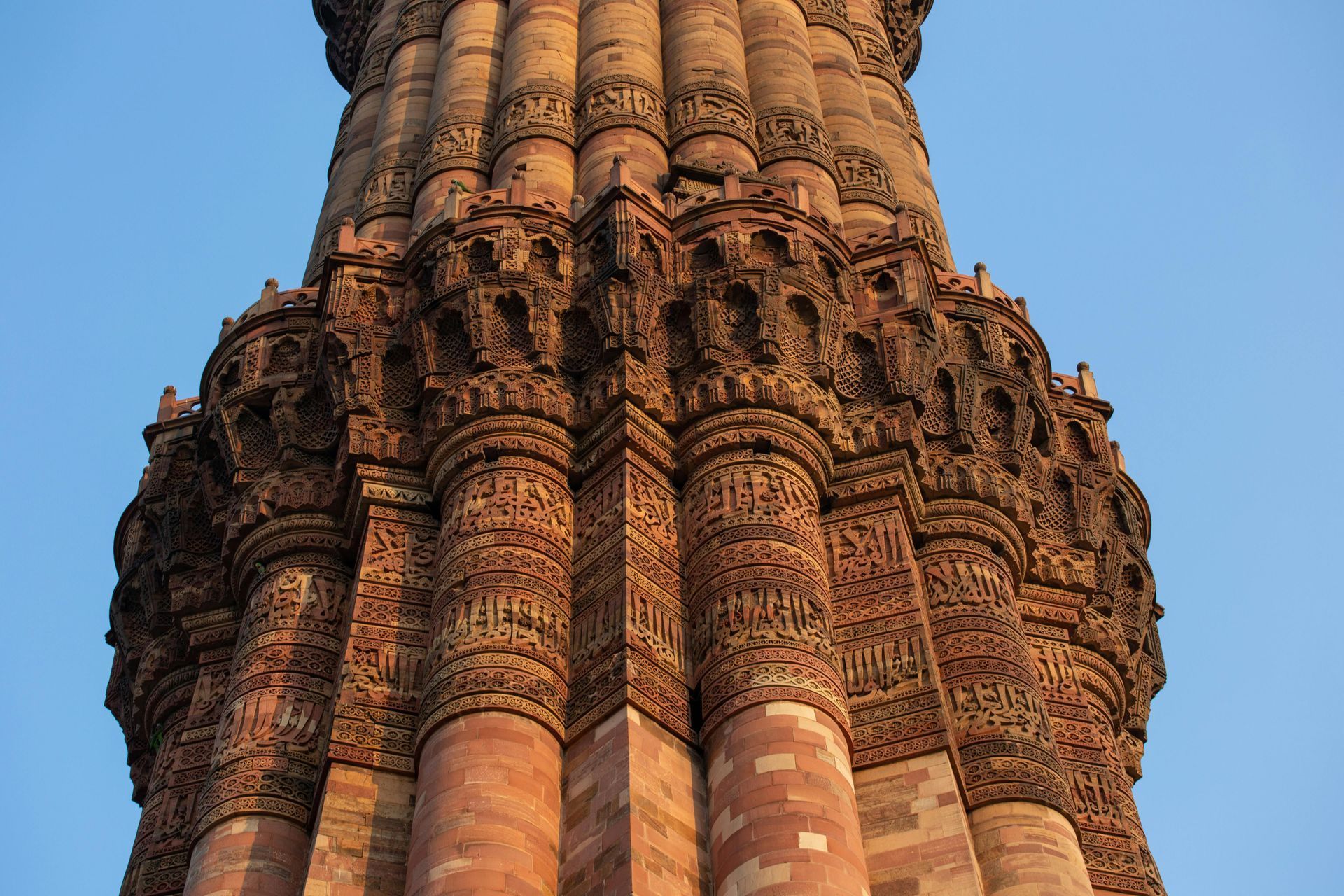 Ornate sandstone temple tower against a blue sky, viewed from below
