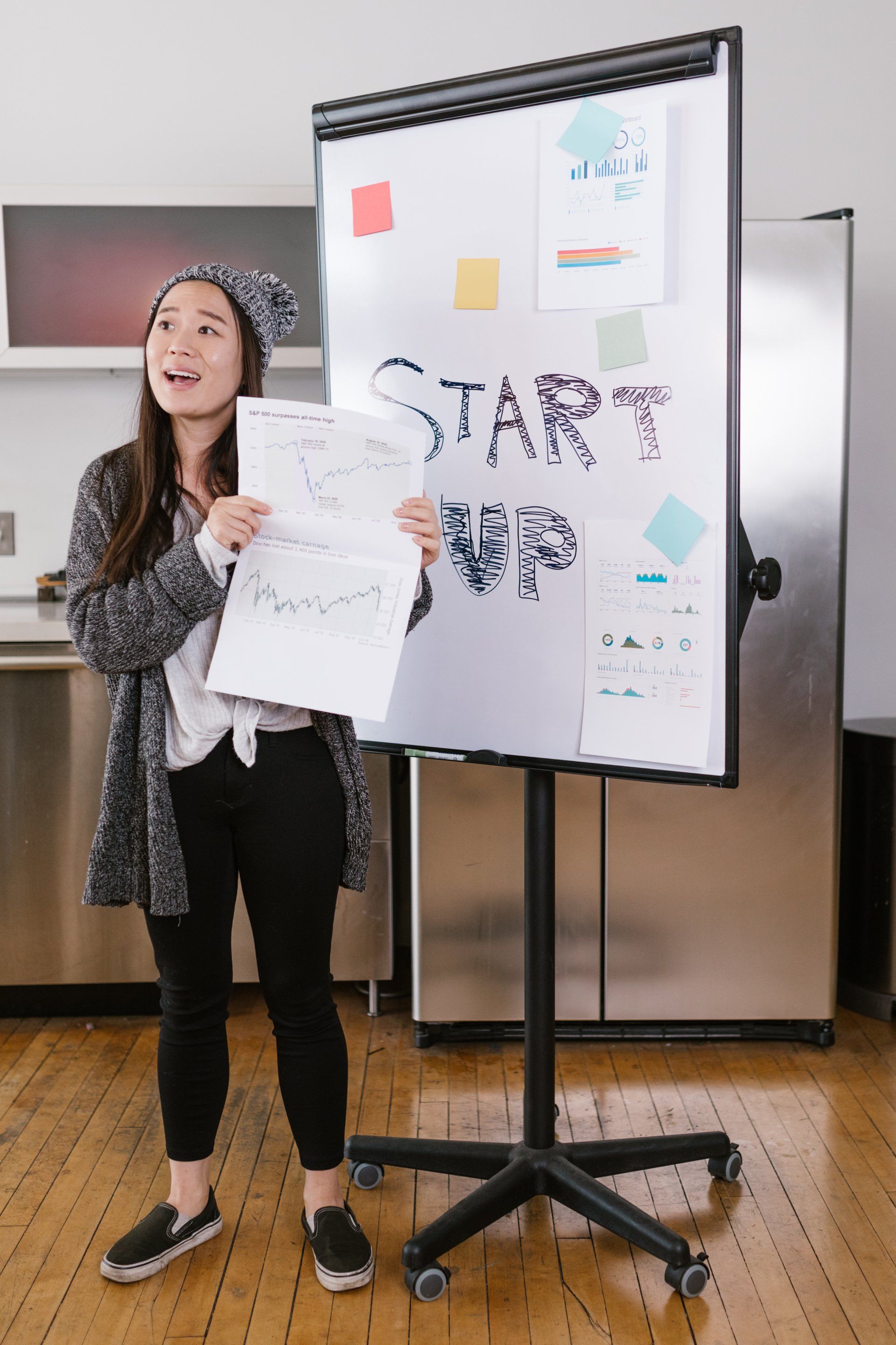 Presenter holding papers beside a whiteboard with “START” in a meeting room