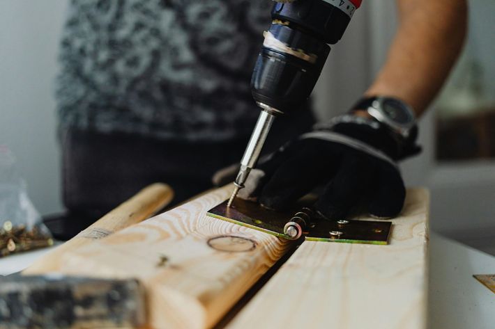 Hand drilling a screw into a wooden plank on a workbench