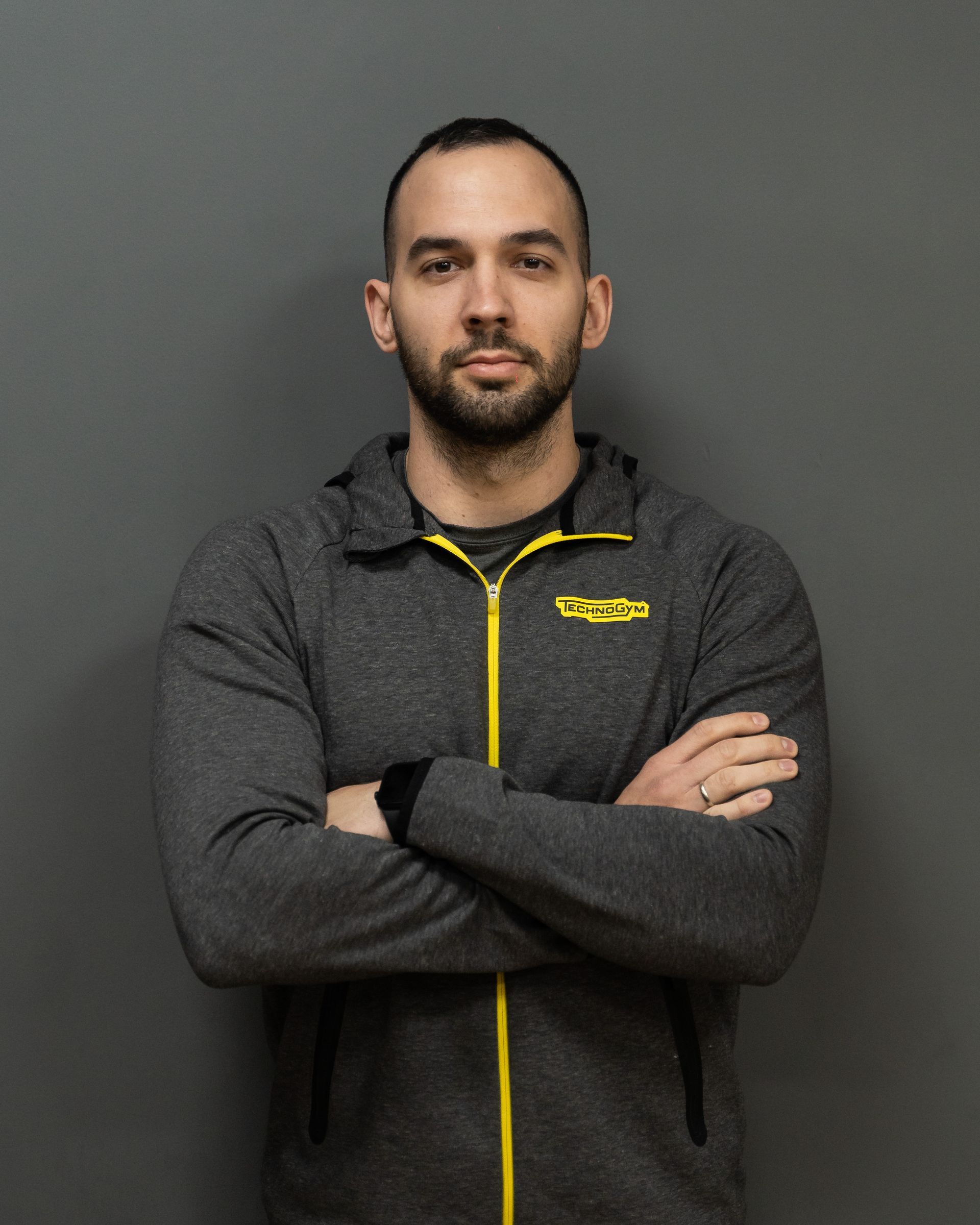a man with his arms crossed is wearing a jacket that says technogym