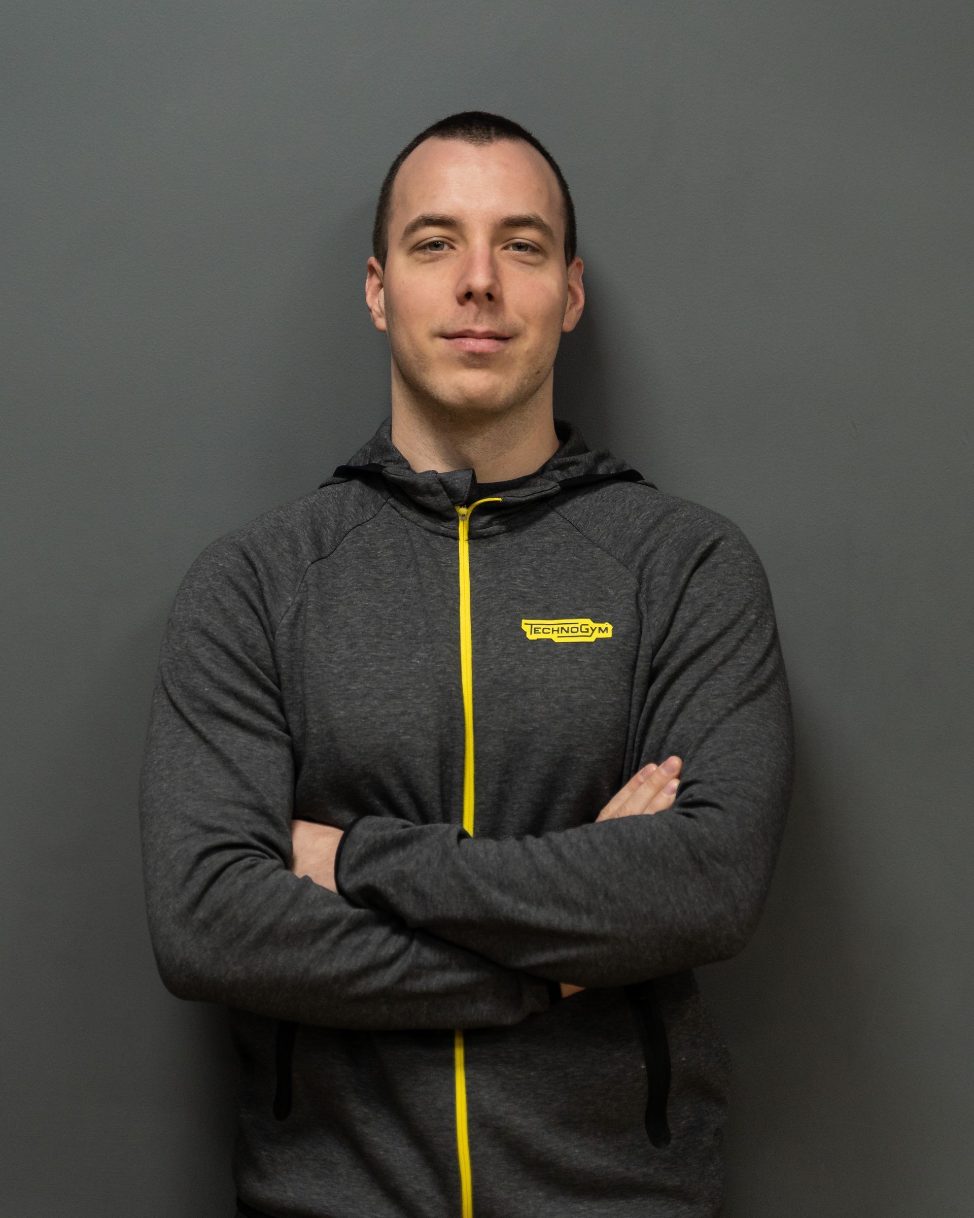 a man with his arms crossed is wearing a technogym jacket