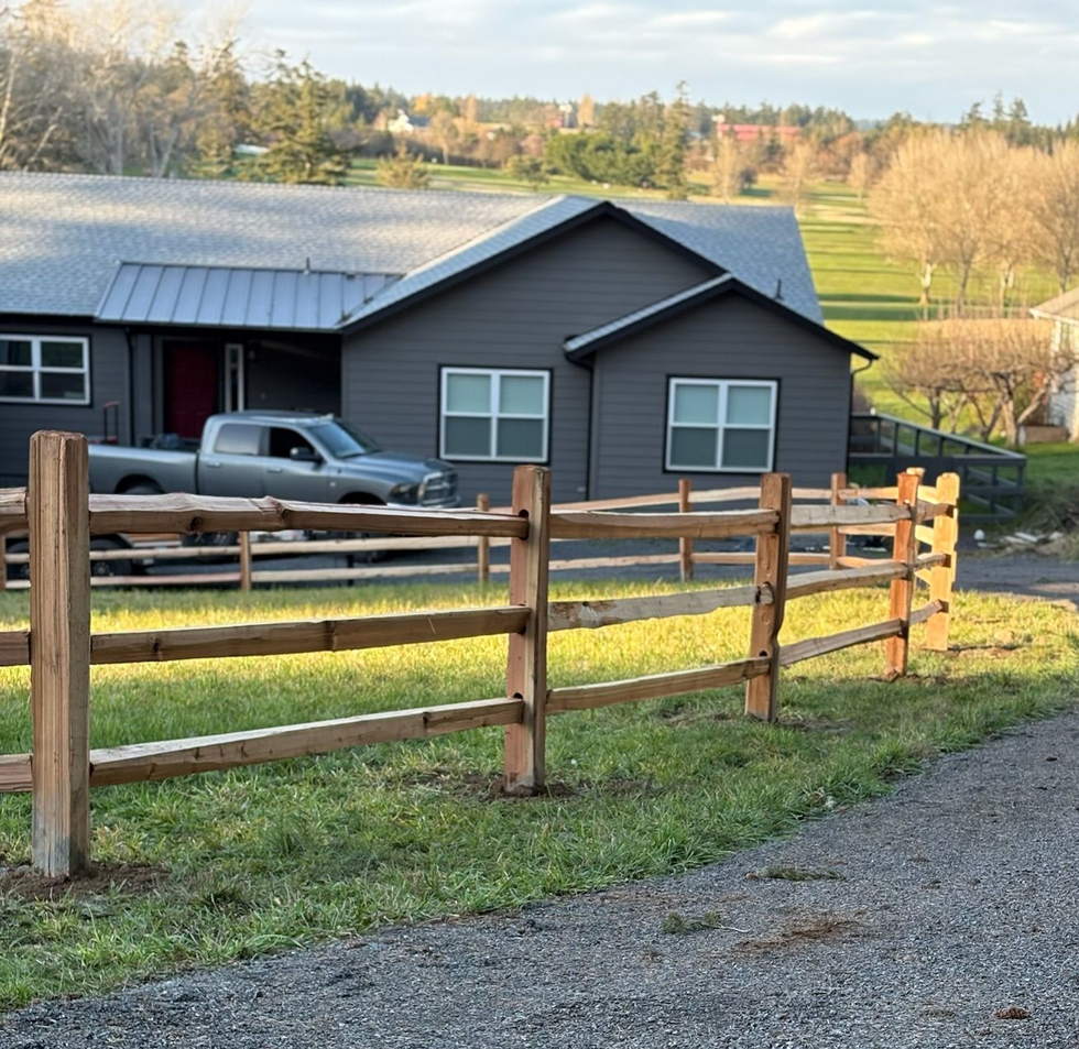 Ranch-style house with a parked pickup truck, wooden fence, and grassy rural yard at sunrise