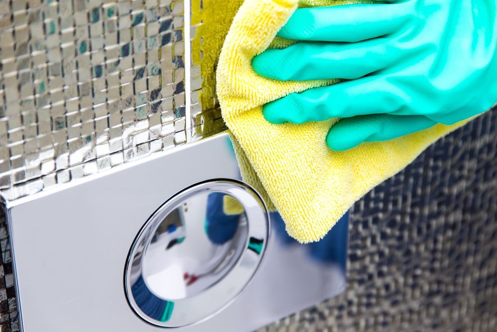 A Person Wearing Rubber Gloves is Cleaning a Toilet With a Cloth — Bali Green Cleaners in Winnellie, NT