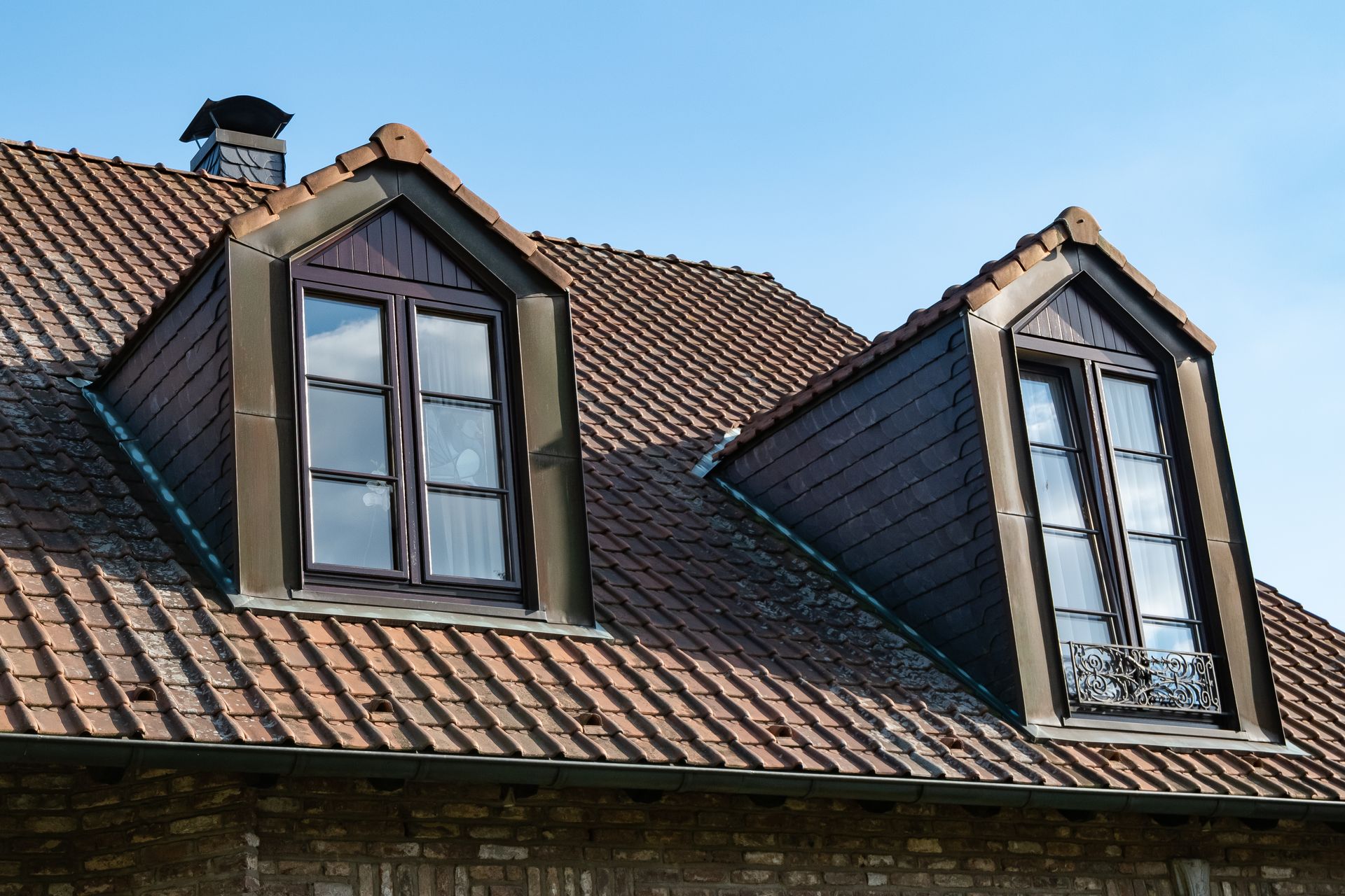 Dormer windows with white frames in clay tile roof showing proper residential window installation
