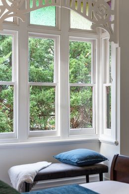 A bedroom with two beds and a bench in front of a window.