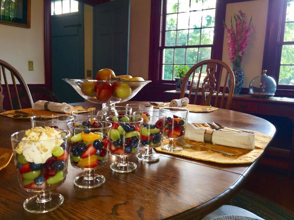 A table with glasses of fruit and a bowl of fruit on it